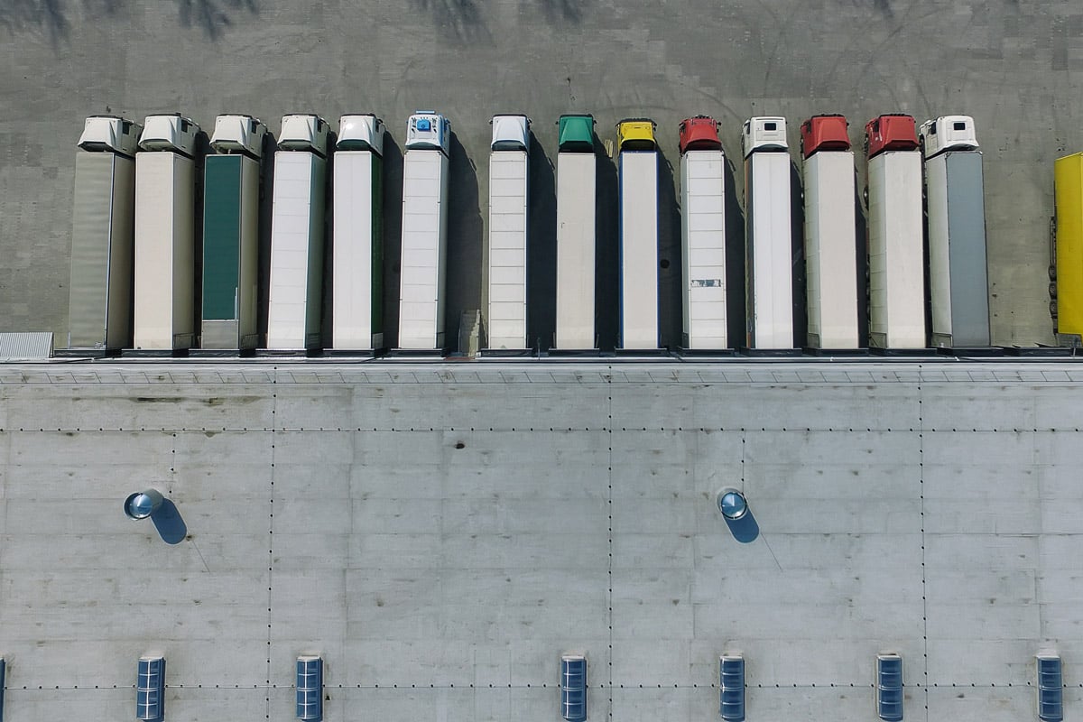 An aerial view of a logistics center in an industrial area with a fleet of HGVs loading